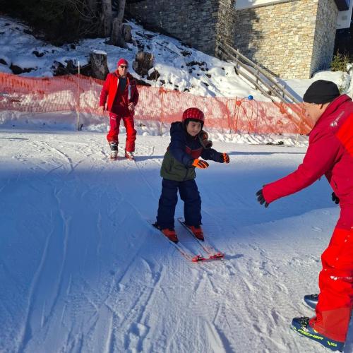 Bub auf Schi wird von Schilehrer aufgefangen