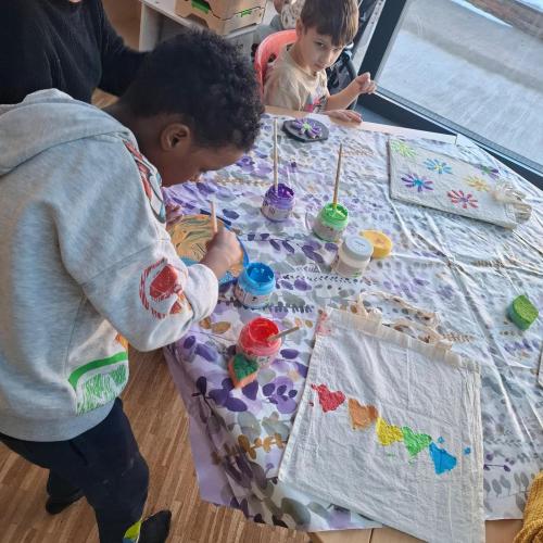 Kinder beim Bedrucken und Bemalen von Stoffbeutel