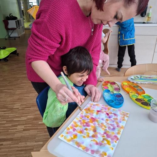 Kind malt mit Assistentin