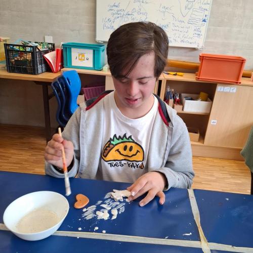 Kind beim Glasieren eines Tonanhängers