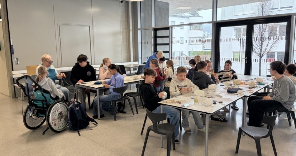 Kinder sitzen um Tische herum und basteln