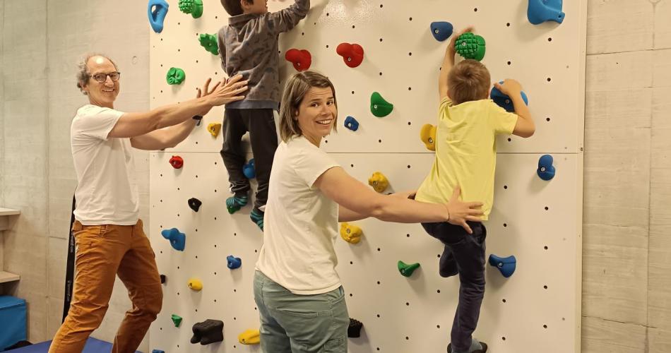 2 Kinder klettern die Kletterwand hinauf und werden von 2 Erwachsenen gesichert