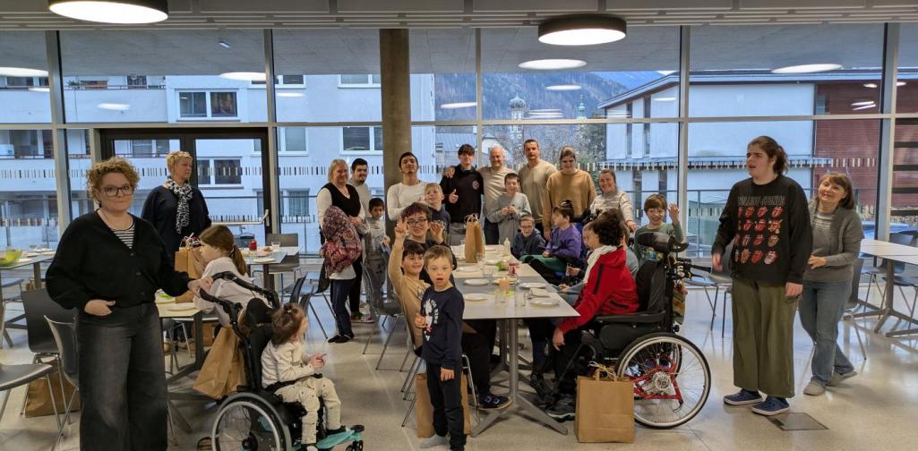 Kinder und Erwachsene stehen um gedeckte Tische