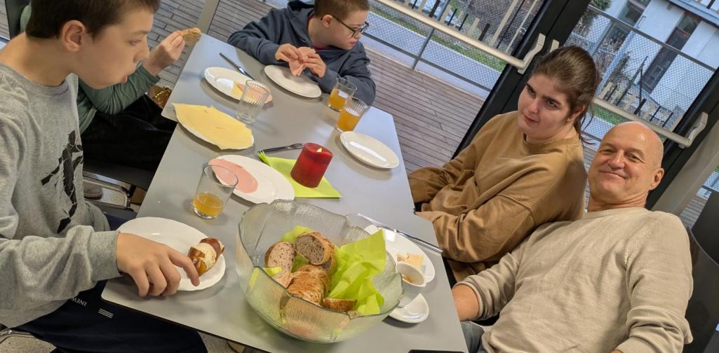 Kinder und Erwachsene sitzen um einen Tisch und essen